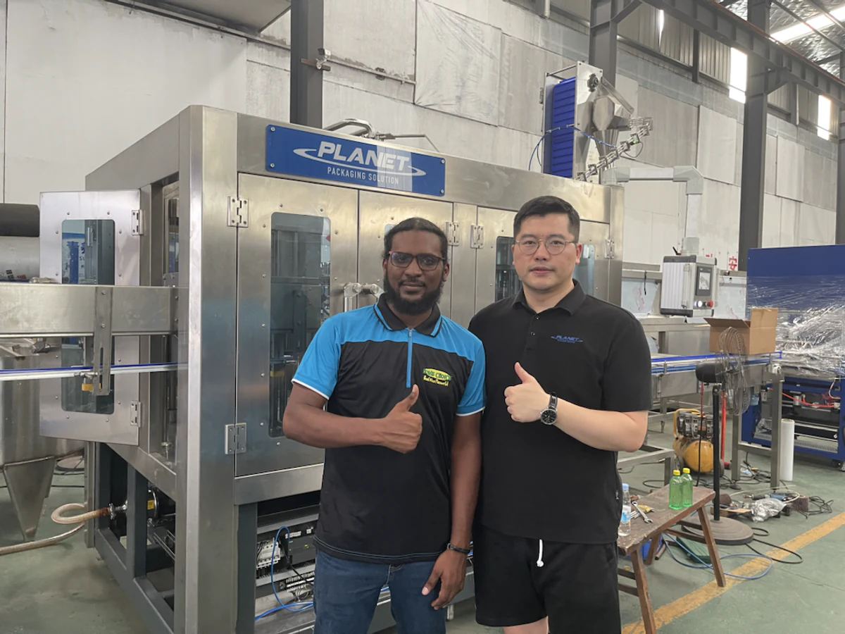 Planet Machinery team and customer beside a PET ginger juice filling line for a project in Jamaica