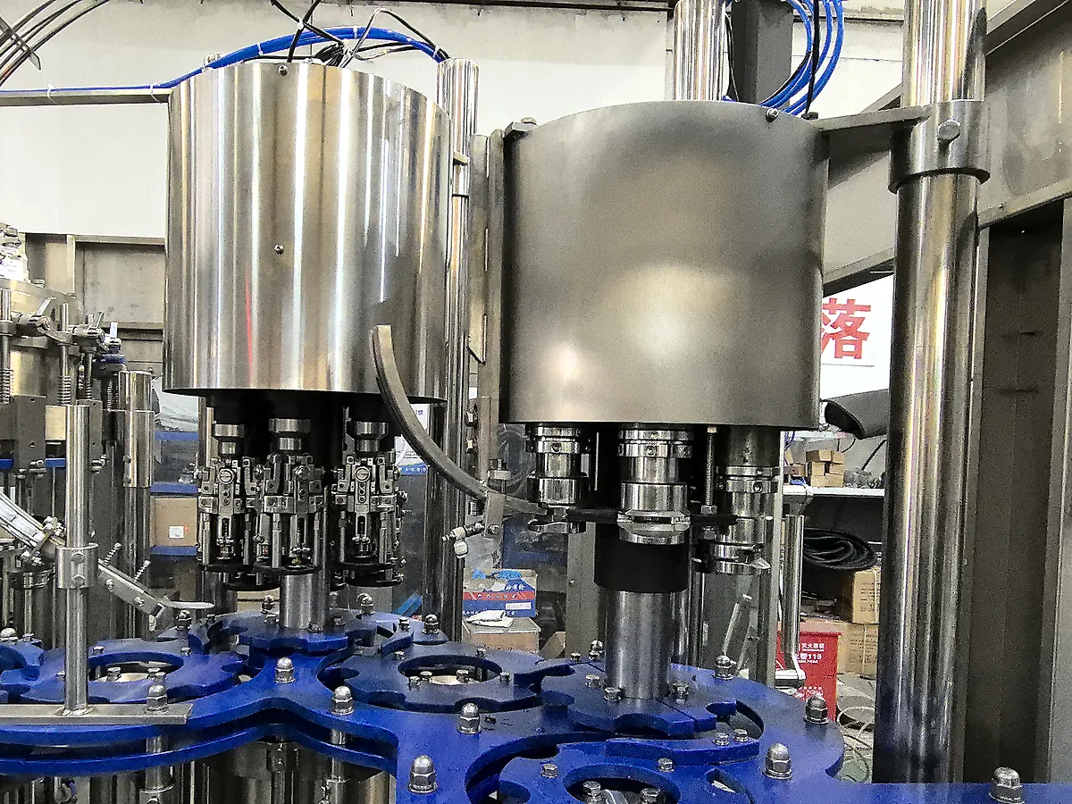 Glass bottle closing and transfer station with stainless-steel closing heads and blue starwheels